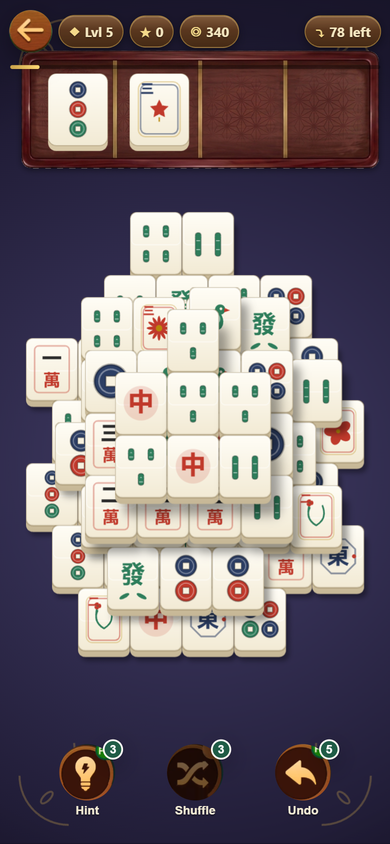 Level 5 on the Dusk table with the Dynasty face set: a stacked pyramid of ivory tiles with bronze-coin dots, characters, dragons, flowers and a sparrow, and two tiles waiting in the wooden tray